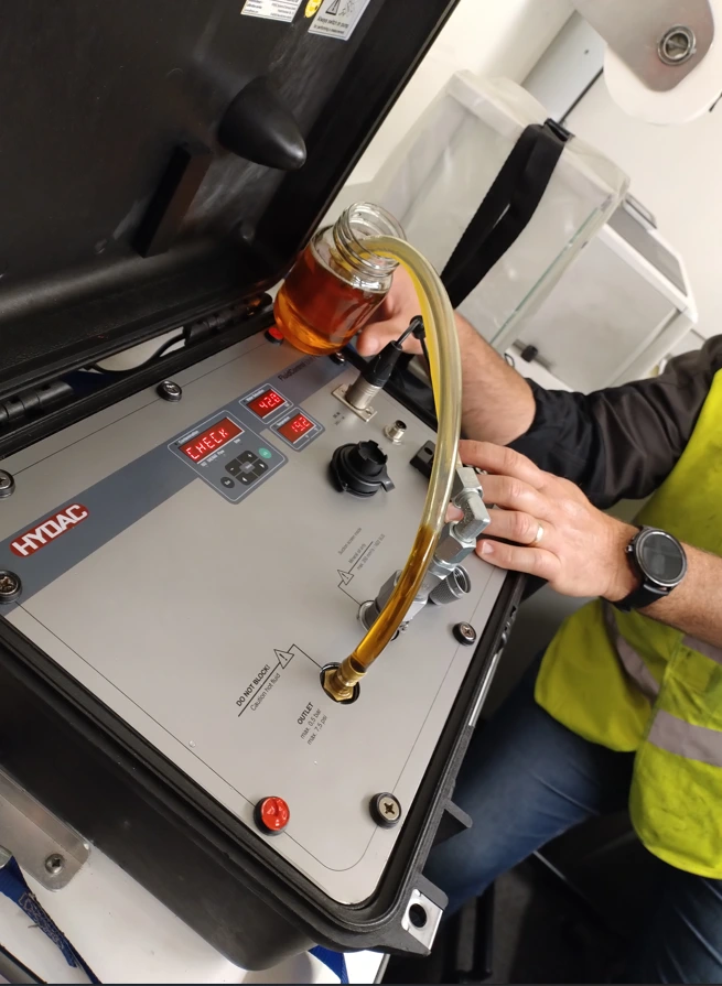 Analyse d'un échantillon d'huile hydraulique à l'aide d'un appareil HYDAC lors d'une intervention de maintenance prédictive sur site.